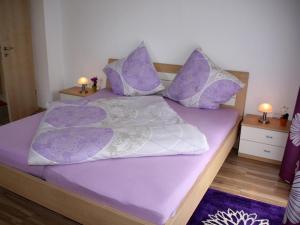 策勒Dogge, Ferienwohnung的一张带紫色和白色床单及枕头的床