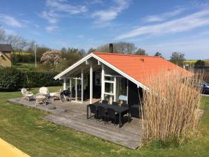 布罗艾厄Two-Bedroom Holiday Home for 6 in Vemmingbund的一座带橙色屋顶和木甲板的房子