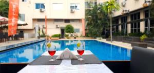 金沙萨Hotel Belle Vie的游泳池畔的桌子上放上两杯酒