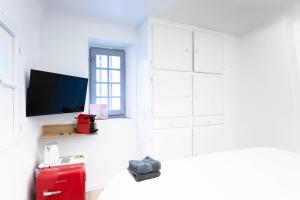 圣特罗佩Villa Sibille - Plein centre de Saint-Tropez的一间白色的房间,配有电视和红色的行李箱