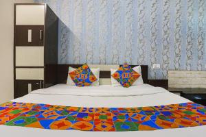 阿拉哈巴德FabHotel Royal Stay Inn的床上有色彩缤纷的毯子和枕头