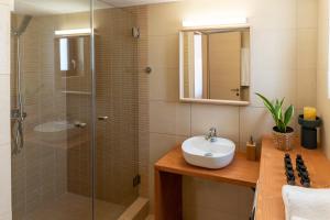 瓦里Syra Suites的一间带水槽和玻璃淋浴的浴室