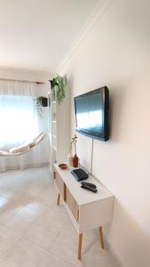 夫塞塔Ria Mar Fuzeta Apartments的客房设有一张桌子,墙上配有电视