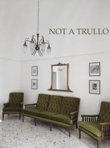 阿尔贝罗贝洛特鲁利迷人酒店的客厅配有两张绿色沙发和镜子