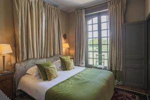 尚皮涅布瑞特尔斯城堡酒店的一间卧室配有一张带绿色枕头的床和一扇窗户