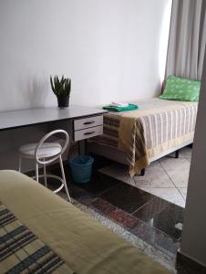 波苏斯-迪卡尔达斯Hotel Pousada Beija Flor的一间卧室配有书桌、一张床和一把椅子