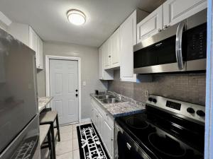 盖恩斯维尔Cozy 2BR Home Near Shands Hospital, UF, and Downtown Gainesville的厨房配有白色橱柜和黑炉灶烤箱。