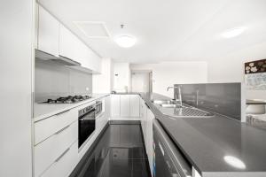 布里斯班Oxygen Apartments的厨房配有白色橱柜和黑色台面