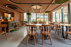 波尔图The Editory Garden Porto Hotel的餐厅设有木桌、椅子和窗户。