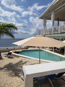 尼格瑞尔Begona Cliff Hotel的一个带遮阳伞的游泳池,位于海边