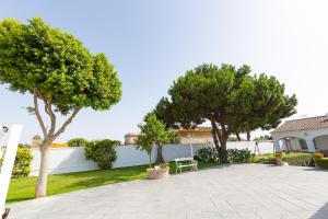 桑卢卡尔-德巴拉梅达Villa las Raices的庭院里种植了两棵树,设有白色的围栏