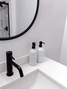 安克雷奇SunStar Alaska Bed and Breakfast LLC的浴室水槽配有2瓶肥皂和镜子