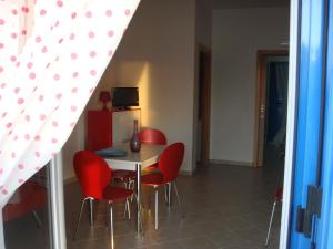 维拉诺瓦Villa ilporticciolovacanze的一间用餐室,配有红色的椅子和桌子