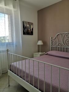 波尔图·埃尔科莱La casa di Ieia的一间卧室配有一张带紫色床单的床和窗户。
