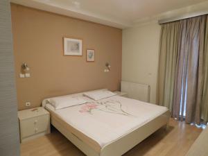 盖夫盖利亚Omeros的一间卧室配有一张铺有白色床单和鲜花的床。