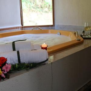 维奥康德马奥Chalés das Orquídeas的浴缸内的蜡烛和毛巾