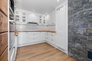 贝特斯托尔Delikat og innbydende leilighet的厨房配有白色橱柜和砖墙