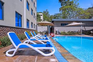 内罗毕Saggys Suites Hotel & Spa的游泳池旁的一排躺椅