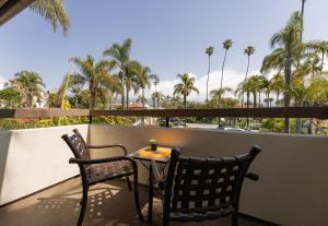 圣巴巴拉The Franciscan Hotel的棕榈树阳台的一张桌子和两把椅子