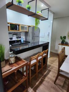 瓜拉派瑞Apartamento Quartos Vista Praia do Morro Casais Melhor Localização, Super Completo 4 TVs Led, Camas-box Novas, 2 Quartos Suíte, Garagem, 2 Ar Condicionados, Wifi 300mb, Varanda Gourmet, Cervejeira, Novo para Famílias的厨房配有黑色柜台和木椅