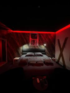 勒米尔蒙spa de la quarterelle LOVE ROOM 88 VOSGES的一间卧室配有一张红色照明的大床