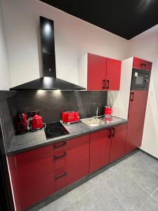 勒米尔蒙spa de la quarterelle LOVE ROOM 88 VOSGES的红色的厨房配有炉灶和水槽
