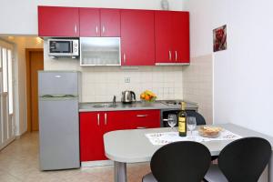斯普利特Katarina apartman的厨房配有红色橱柜和白色桌椅