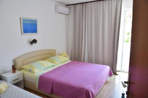 拉布Guest house Tina的一间卧室配有一张大床和紫色毯子