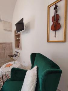 马丁纳弗兰卡ROSSINI GUEST HOUSE的客厅配有绿色沙发和墙上的小提琴