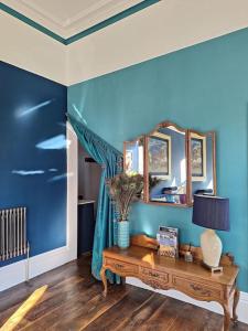巴克斯顿The Huntress Suite的蓝色的客房配有桌子和镜子