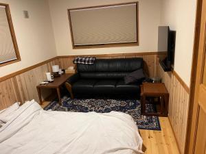 MatsukawaKaburo no Niwa Grand Campsite - Vacation STAY 98272v的客厅配有黑色真皮沙发和电视
