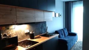 华沙Apartament Wawa的一间带蓝色沙发的客厅和一间厨房