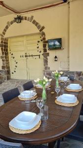 圣焦万尼达索VAL D'ORCIA DELUXE 3, incantevole casa con vista sulle colline, WiFi e parcheggio的一张木桌,上面放有盘子和酒杯