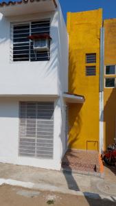 RELAJACION SERCAS DEL AEROPUERTO的黄色和白色的建筑,窗户上摆放着椅子