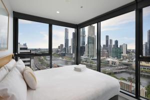 墨尔本The Canvas Apartment Hotel的一间配备有白色床的卧室,享有城市美景。