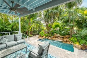 基韦斯特Tropical Retreat的一个带游泳池、沙发和椅子的户外庭院
