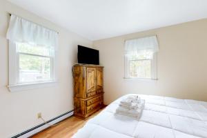 海恩尼斯Hyannis Beach House的卧室配有白色的床和梳妆台上的电视