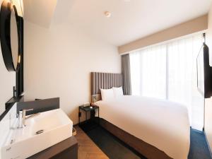 福冈QuintessaHotel FukuokaHakata Relax&Sleep的浴室设有白色的床和水槽。