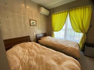 宜野座Ｂ＆ＢTandem的一间卧室设有两张床,窗户配有黄色窗帘