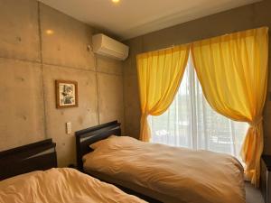 宜野座Ｂ＆ＢTandem的一间卧室设有床和黄色窗帘的窗户