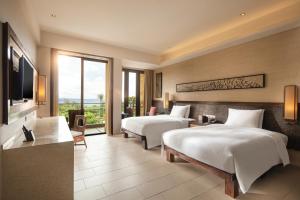 三亚三亚海棠湾万达嘉华度假酒店的酒店客房设有两张床和电视。