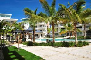 蓬塔卡纳Lumina at Jardines Punta Cana Village的一个带游泳池和棕榈树的度假村