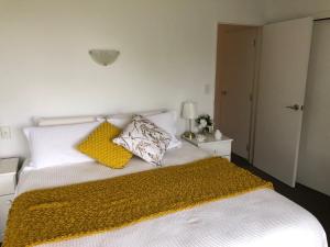 One Tree PointLuxury Waterfront的一张带两个枕头的白色床和黄色毯子