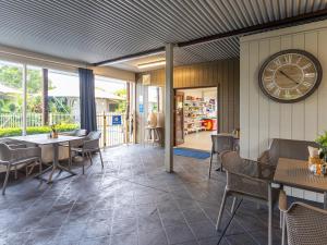 坦卡里NRMA Forster Tuncurry的餐厅设有墙上的时钟和桌椅