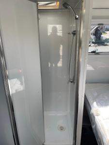 金德拜恩Jindabyne caravan hire的一张床旁边的玻璃门淋浴