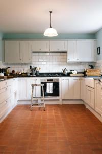 HawardenGardener's House - Hawarden Estate的厨房配有白色橱柜和凳子