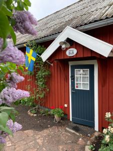 FörslövFogdarps B&B -Eget gästhus-的一座红色的房子,有蓝色的门和旗帜