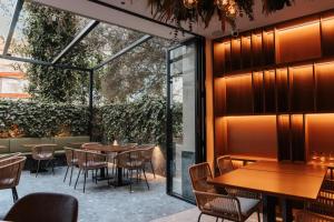 加的斯Boutique Hotel OLOM - Only Adults recommended的餐厅设有木桌、椅子和玻璃墙