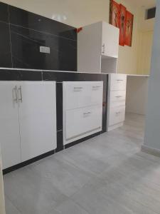 达喀尔Studio Emeraude - cosy et climatisé - Résidence Saraba Mermoz的厨房配有白色橱柜和黑色台面