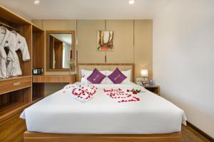 岘港Lavender Riverside Hotel的卧室配有一张白色大床,床上有红色的鲜花